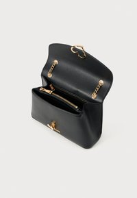 Μαύρη δερμάτινη τσάντα χειρός με στρογγυλεμένο σχήμα, χρυσαφένιες μεταλλικές λεπτομέρειες και διπλό φερμουάρ στο εσωτερικό. Διαθέτει αλυσίδα στη θήκη κλεισίματος.