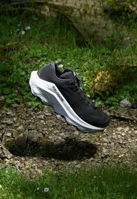 Baskets de sport noires avec un dessus en synthétique texturé, une semelle intermédiaire blanche contrastante et des lacets. Design léger avec une semelle rembourrée.