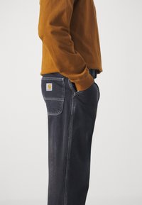Mørke denimjeans med rett passform og synlige sømmer, med en lomme med logo bak. Materiale i bomullsblanding.