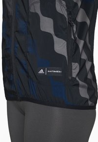 Giacca a vento con motivo a onde in tonalità di blu e grigio, con il logo adidas e marimekko sull'orlo, tessuto strutturato.