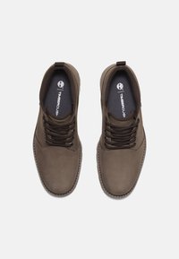 Brown leather shoes with lace-up design, round toe, padded collar, and textured rubber sole. Logo visible on insole.