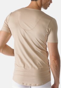 Beige kortärmad t-shirt med en mjuk textur och rund nederkant. Har en subtil böjd söm över den övre ryggen.