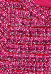 Rosa tweedtyg med intrikata texturerade mönster med röda och vita accenter, som framhäver en rutnätsdesign och mjuk textur.