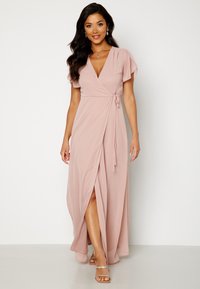 Abito avvolgente rosa chiaro con maniche a sbuffo corte, scollatura a V profonda e uno spacco laterale, realizzato in un morbido tessuto fluido. Design casual ed elegante.