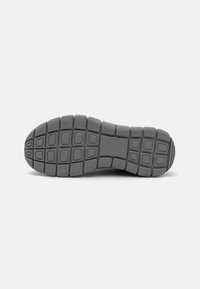 Gray rubber shoe sole featuring a textured pattern with square and rectangular treads for enhanced grip and shock absorption.