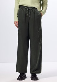 Groene, losse cargobroek van gladde, glanzende stof, met een elastische tailleband met trekkoord en twee zijzakken.