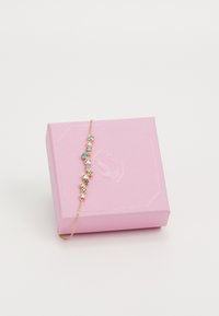 Gold bracelet with multi-colored crystals in a graduated pattern, resting on a pink gift box featuring a swan logo.