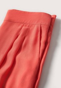 Koraal pluizige blouse met een zachte textuur, voorzien van een wijde halslijn en gerimpelde details op de schouders, ontworpen voor een ontspannen pasvorm.