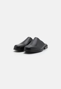 Černé kožené nazouvací boty s hladkým povrchem, kulatou špičkou a nízkým, obdélníkovým podpatkem. Minimalistický design bez viditelných ozdob.
