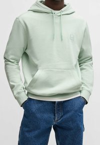 Mátově zelená mikina s kapucí z měkké látky, s klokaní kapsou, nastavitelnou kapucí se stahovací šňůrkou a malou logovou nášivkou na hrudi.