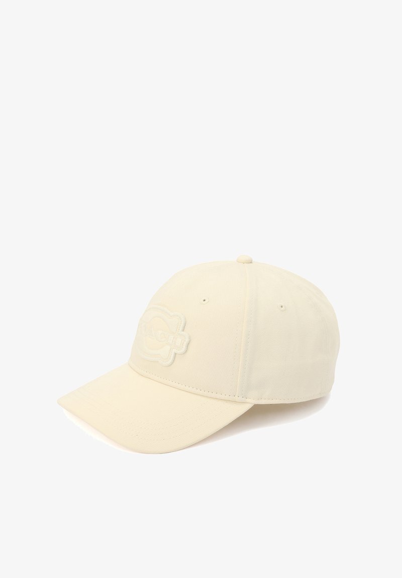 Casquette de couleur crème en tissu avec un design structuré. Elle présente un écusson brodé avec un logo sur le devant et une visière incurvée.
