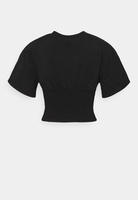 Camiseta corta negra con mangas cortas y anchas, cintura elástica y textura de tela suave. Cuello redondo simple y diseño minimalista.