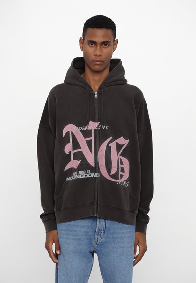 Sweat à zip noir en tissu doux. Présente un texte graphique rose vif sur le devant, avec une poche kangourou et une capuche à cordon.