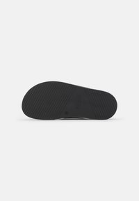 Talpa de adidasi din cauciuc negru cu un model texturat, având striații pentru aderență și un mic logo al mărcii pe lateral.