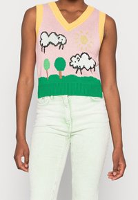 Gilet sans manches en tricot de couleur rose, jaune et verte, avec des motifs de moutons, d'arbres et de soleil. Ourlet côtelé et décolleté en V.