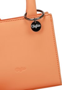 Borsa a mano sintetica arancione con una texture liscia, dotata di un accento circolare in metallo argentato e dettaglio del logo impresso.