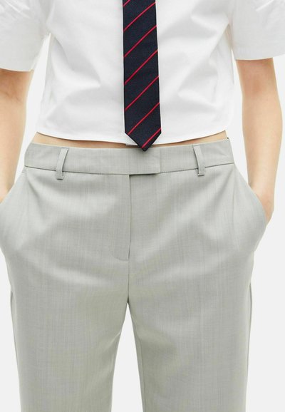 Lichtgrijze pantalon met een soepele textuur, voorzien van zijzakken en een rechte voorkant, gecombineerd met een witte overhemd met korte mouwen en een marineblauw gestreepte das.