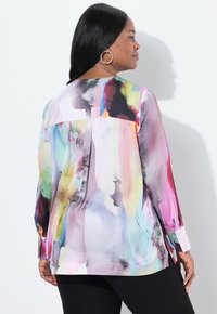 Bunte, gemusterte Bluse mit lockerer Passform, langen Ärmeln, abgerundetem Saum und geknöpften Manschetten in den Farben Pink, Blau, Grün und Schwarz.