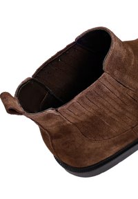 Stivaletto in suede marrone con pannelli laterali elasticizzati, dettagli rigati e suola in gomma nera. L'interno è foderato per il massimo comfort.