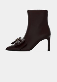 Rudi od tamsiai rudos odos auliniai batai su smailia nosimi, aukštu stiletto kulnu ir dekoratyvine juostele šone. Lygus paviršius, elegantiškas dizainas.