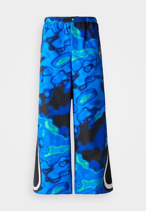 Blaue und schwarze, abstrakt gemusterte, weit geschnittene Hose mit elastischem Bund und seitlichen Reißverschlusstaschen auf einem einfarbigen Hintergrund.