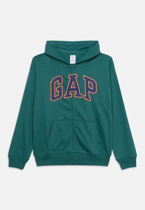 Zelena jopica z zadrgo in kapuco, s kengurujim žepom ter velikim logotipom "GAP" v mornarsko modri barvi z oranžnim robom na sprednji strani.