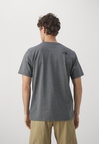 Gray short-sleeve t-shirt with a round neckline and black logo detail on the upper back. Fabric appears soft and textured.