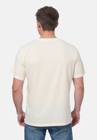 Pánske tričko s krátkym rukávom v svetlo krémovej farbe vyrobené z bavlny. Má okrúhly výstrih a rovný strih. Minimalistický dizajn; žiadne viditeľné vzory ani akcenty.
