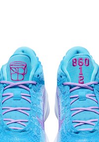 Blaue Sportschuhe mit einem strukturierten Mesh-Obermaterial, lavendelfarbenen Schnürsenkeln und pinken Markierungsdetails an der Zunge. Bietet markante Designelemente.
