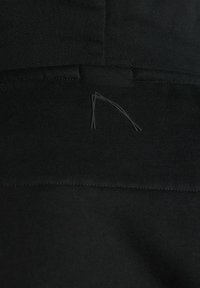 Vêtements de sport noirs en tissu lisse et extensible, avec une conception sans coutures et un détail de couture subtilement incurvé.