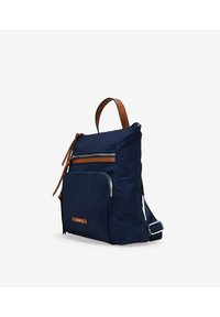 Bolsa de nylon azul marino con detalles en cuero marrón, que cuenta con un compartimento principal, un bolsillo frontal con cremallera y una correa ajustable. Forma rectangular compacta.