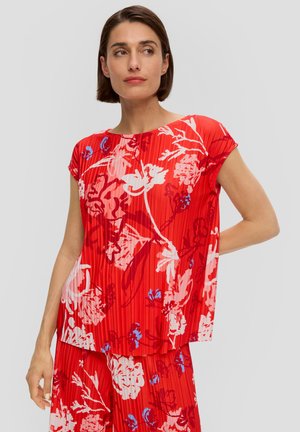 Blouse rouge à fleurs avec des manches courtes, présentant une texture plissée et des motifs abstraits dans des tons de rose et de bleu.