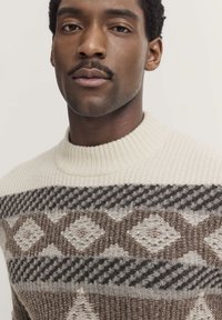 Maglione lavorato a maglia color crema, con un motivo a diamanti e houndstooth in marrone e grigio. Collo a costine e tessuto testurizzato.