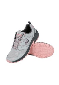 Zapatilla deportiva gris con acentos rosas, parte superior de malla, suela acolchada y piso texturizado. Presenta cordones y una etiqueta de tirón para facilitar el calzado.