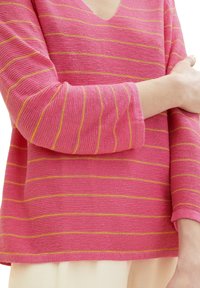 Rosa gestreifter Pullover mit V-Ausschnitt und drei Viertelärmeln. Verfügt über horizontale gelbe Streifen und einen strukturierten Strickstoff.