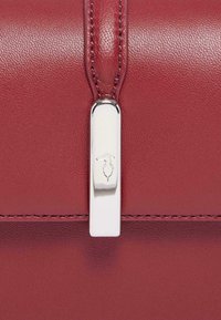 Borsa a tracolla rossa in pelle con una superficie liscia, chiusura in tonalità argento e cuciture decorative lungo i bordi.
