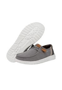 Scarpe di tela grigie con una suola bianca maculata, dotate di un dettaglio in pelle marrone e un tallone testurizzato. Design con lacci e punta arrotondata.