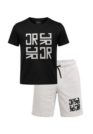 T-shirt nera a maniche corte con stampa geometrica bianca abbinata a pantaloncini a vita elastica color avorio con stampa nera coordinata sulla gamba sinistra.