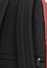 Černý a růžový batoh s polstrovanými popruhy, hladkým materiálem a detailním zipovým uzávěrem. Nabízí elegantní design s kontrastními barvami.