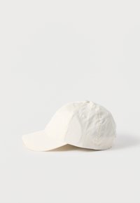 Εκρού καπέλο μπέιζμπολ με εξάπτυχα ραφές, οπές αερισμού και κυρτό γείσο, τοποθετημένο σε λευκή επιφάνεια.