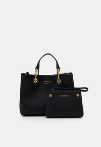 Set di borse in pelle nera composto da una borsa più grande con hardware dorato e una pochette più piccola con un manico da polso, entrambe texture.