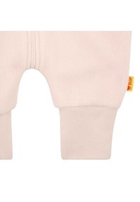 Pantalons pour bébé en polaire rose clair avec une fermeture éclair à l'avant et des poignets côtelés ; présente une petite étiquette de logo jaune. Texture douce et design décontracté.