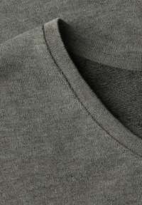Maglione grigio a V in tessuto lavorato. Il colletto presenta un design a coste e il materiale sembra morbido e leggero.
