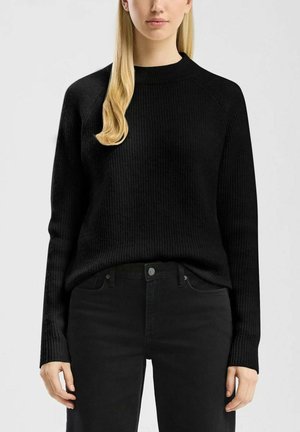 Zwart geribbeld sweatshirt met lange mouwen en een ronde hals, gecombineerd met zwarte jeans. De stof lijkt zacht en heeft een gestructureerde afwerking.