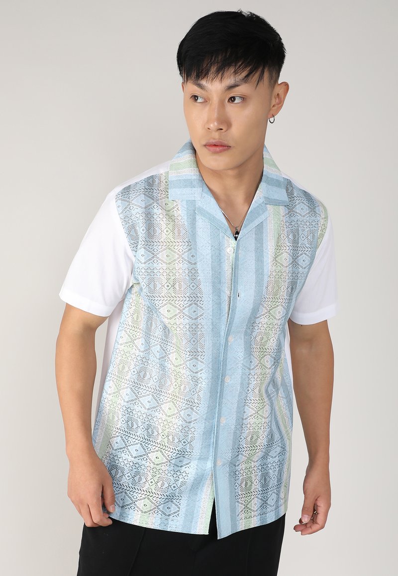 Chemise à manches courtes présentant un devant bleu à motifs avec des designs géométriques et des accents verts, complétée par un dos et un col en coton blanc.