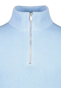 Ljust blå ribbad polotröja med en fjärdedelsdragkedja, med vertikala linjer och en mjuk textur. Dragkedjan har en metallisk finish.