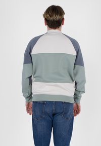 Felpa in morbido tessuto, caratterizzata da un design color block con sezioni verdi, grigie e crema. Polsini a costine e vestibilità comoda.