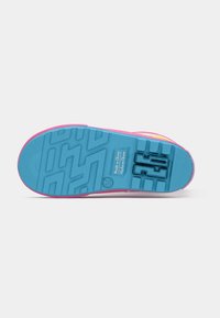 Semelle d'une sneaker pour enfant avec semelle bleue, bords roses, marquage de taille 26 et texte "Fabriqué en Chine".