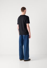 Black short-sleeve t-shirt paired with wide-leg blue denim jeans. The t-shirt has a simple design, while the jeans feature a high waist and relaxed fit.
