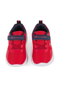 Zapatillas deportivas rojas con parte superior de malla, acentos en azul marino, cordones y correa ajustable. Presentan una suela blanca con un patrón de zigzag en la parte superior.